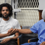 J. Cole at the San Quentin Media Center shaking hands with Miguel Sifuentes