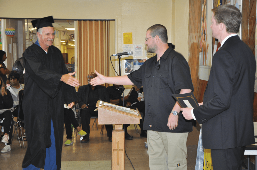 Graduate Thomas Colt to shakes hands with Instructor Leonida and Principal Wheelis