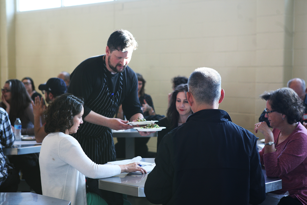 Chef Huw serving food prepared by the graduates