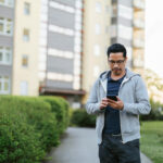Man using smart phone by apartment building