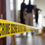 crime scene tape in building with blurred forensic team backgrou