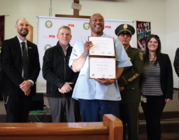 Last Mile graduate Wilbert Frank poses for a photo flanked by CALPIA and SQ administrators